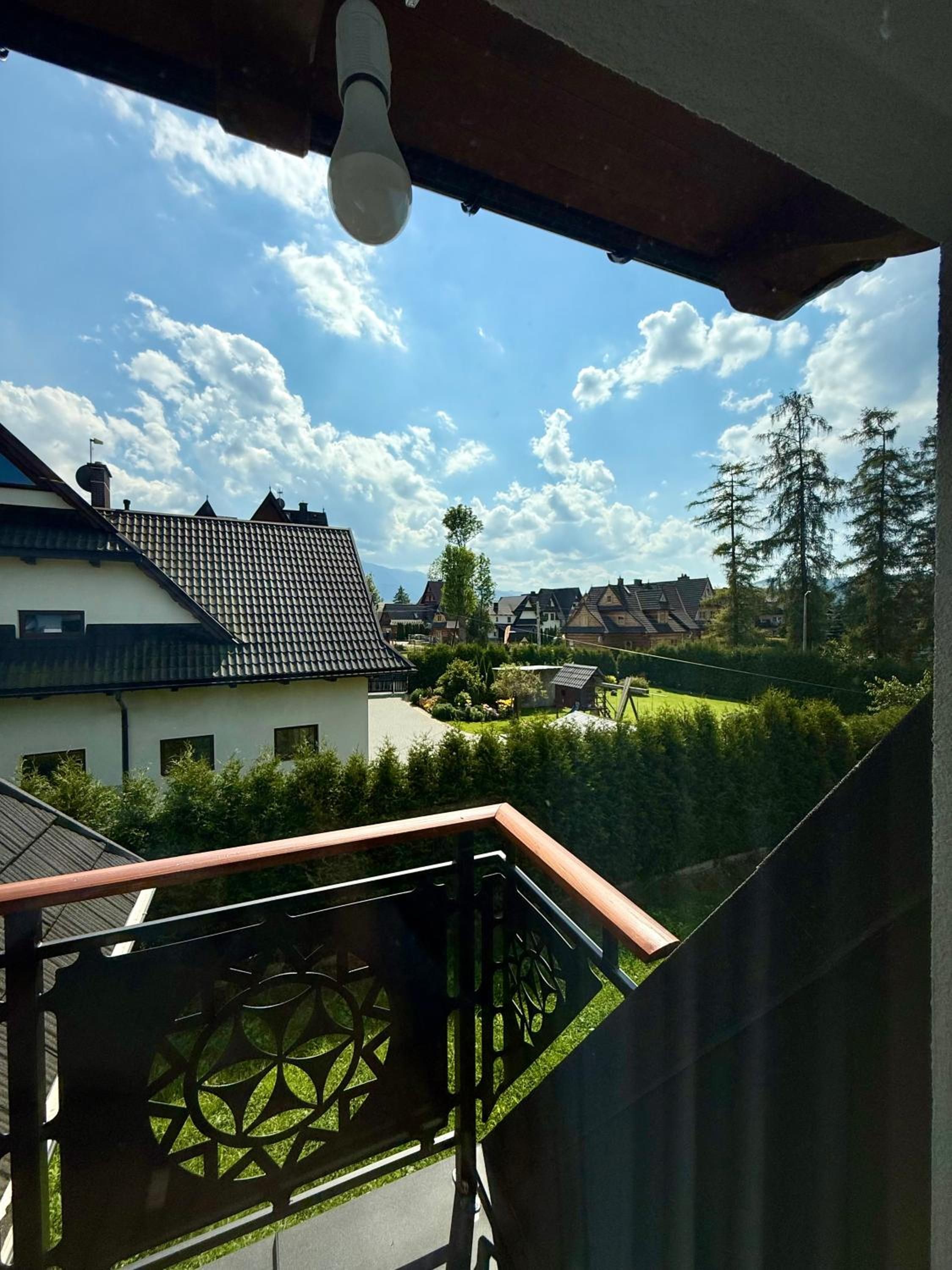 Widok z balkonu na zieleń i sąsiednie domy